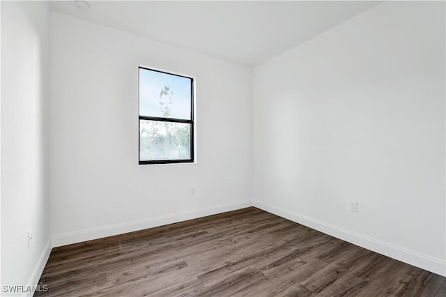 spare room with baseboards and wood finished floors