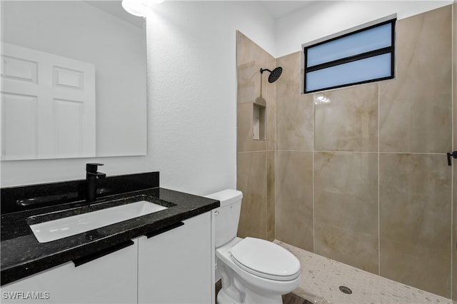 bathroom featuring tiled shower, vanity, and toilet