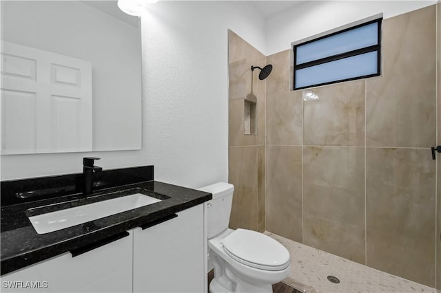 full bath featuring vanity, a tile shower, and toilet