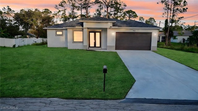 view of front facade featuring driveway, an attached garage, fence, a front yard, and stucco siding