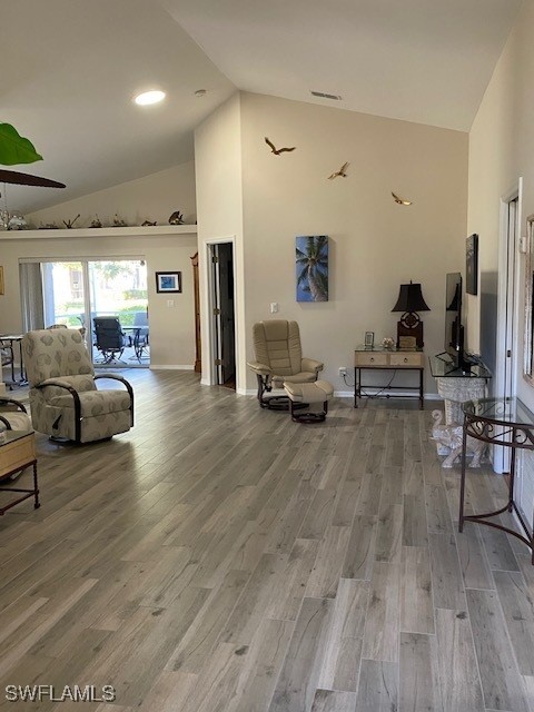 living room featuring high vaulted ceiling and hardwood / wood-style flooring