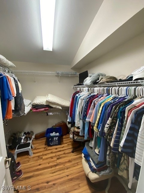 walk in closet with hardwood / wood-style flooring and lofted ceiling