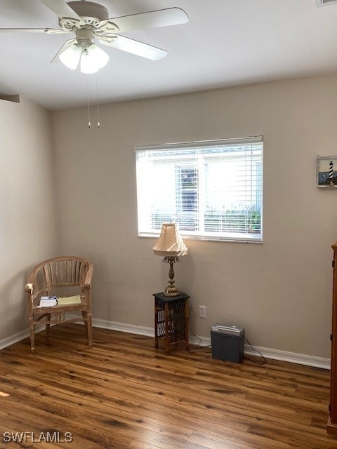 living area featuring ceiling fan and dark wood-type flooring