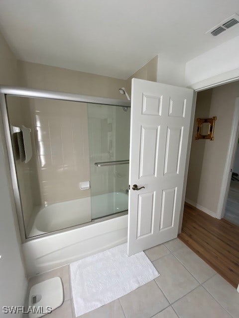 bathroom with tile patterned floors and bath / shower combo with glass door