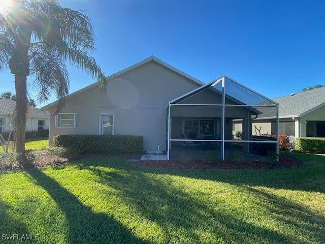 13358 Queen Palm Run, North Fort Myers, FL 33903 - back of property with a sunroom, a lawn, and stucco siding