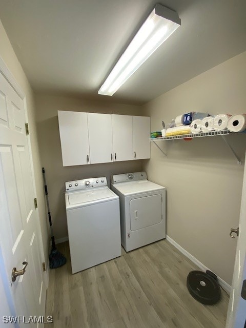 washroom featuring cabinets, light hardwood / wood-style flooring, and washer and clothes dryer