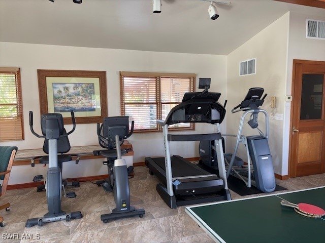 workout area featuring track lighting and vaulted ceiling