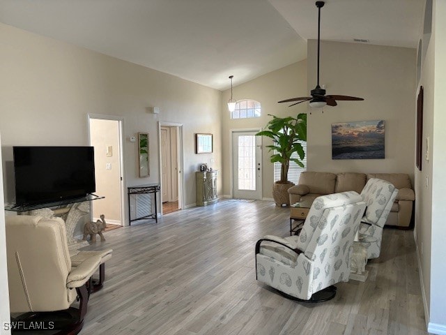 living room featuring light hardwood / wood-style floors, high vaulted ceiling, and ceiling fan