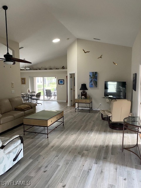 living room with hardwood / wood-style flooring, high vaulted ceiling, and ceiling fan