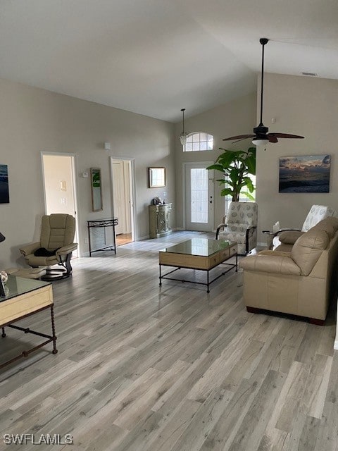 living room with ceiling fan, high vaulted ceiling, and light hardwood / wood-style floors