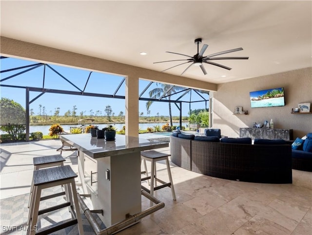 view of patio with a lanai, exterior bar, an outdoor living space, ceiling fan, and a water view