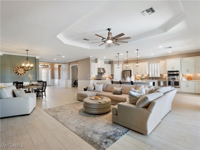 living room with a tray ceiling, light hardwood / wood-style flooring, and a healthy amount of sunlight