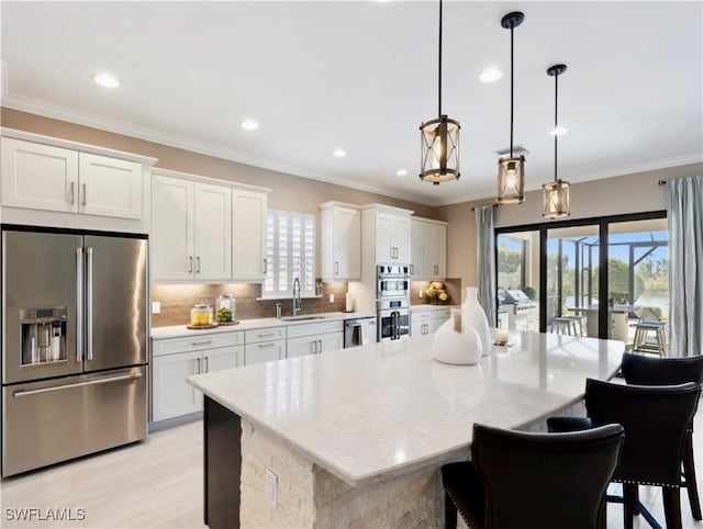 kitchen featuring pendant lighting, white cabinets, sink, a kitchen island, and stainless steel appliances