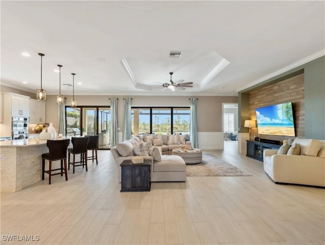 living room with ceiling fan, ornamental molding, and light hardwood / wood-style flooring