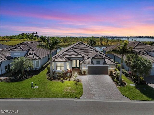 mediterranean / spanish house with a lawn, a garage, and a water view