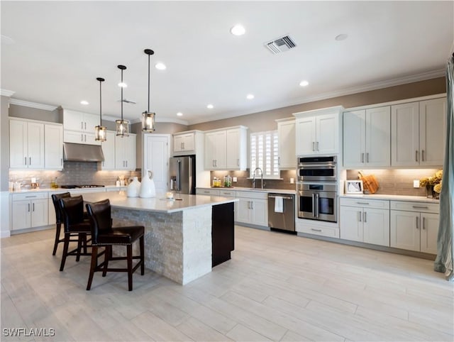 kitchen featuring appliances with stainless steel finishes, sink, a kitchen island, hanging light fixtures, and a breakfast bar area