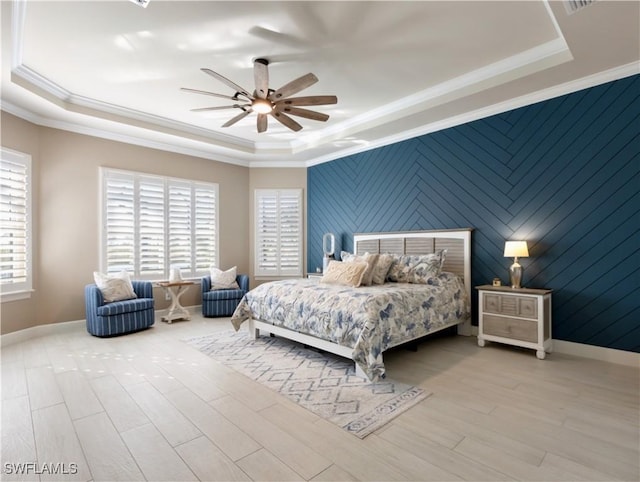 bedroom with ceiling fan, crown molding, light hardwood / wood-style flooring, and a tray ceiling