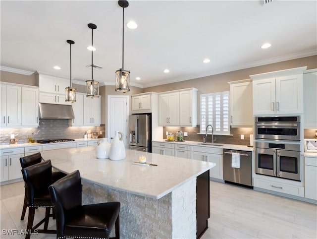 kitchen with pendant lighting, a center island, sink, a kitchen bar, and stainless steel appliances