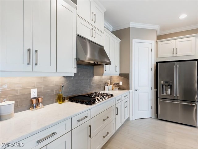 kitchen with stainless steel appliances, tasteful backsplash, light hardwood / wood-style flooring, white cabinets, and ornamental molding