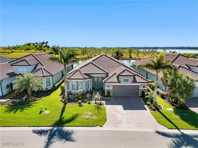 mediterranean / spanish-style house featuring a water view, a garage, and a front lawn