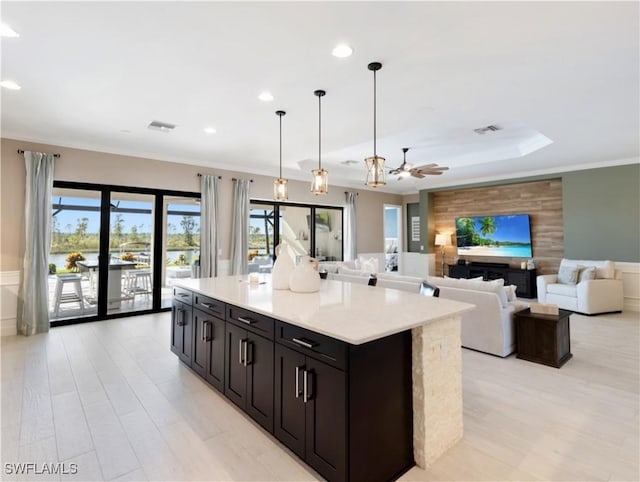 kitchen featuring ceiling fan, light hardwood / wood-style flooring, decorative light fixtures, a fireplace, and a kitchen island