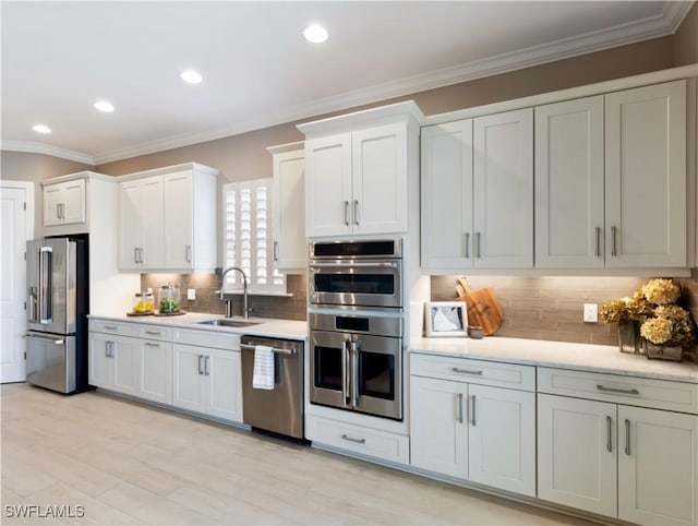 kitchen with backsplash, crown molding, sink, appliances with stainless steel finishes, and white cabinetry