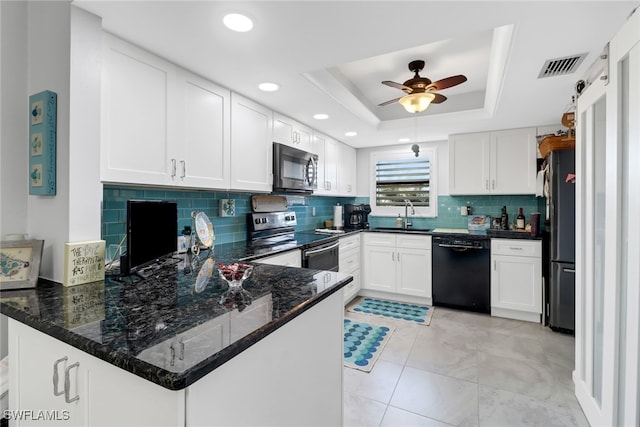 kitchen with kitchen peninsula, ceiling fan, a tray ceiling, white cabinetry, and stainless steel appliances