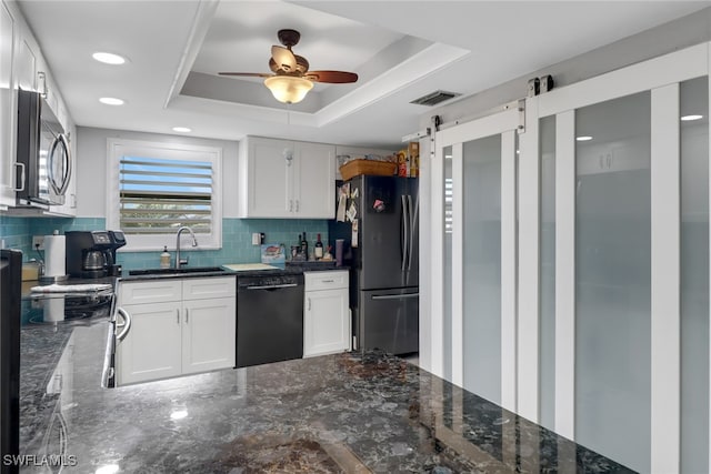 kitchen with a barn door, a raised ceiling, white cabinetry, and stainless steel appliances