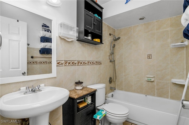 full bathroom featuring tiled shower / bath, toilet, tile walls, and sink