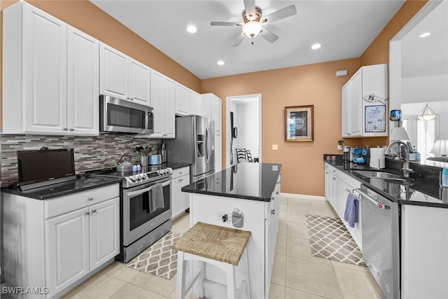 kitchen with decorative backsplash, stainless steel appliances, a kitchen island, sink, and white cabinetry