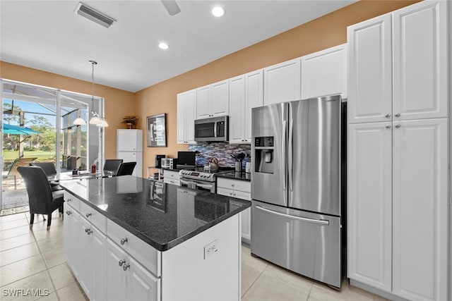 kitchen with appliances with stainless steel finishes, dark stone counters, a kitchen island, and white cabinets