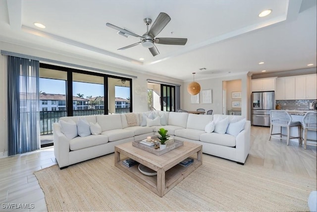 living room with ceiling fan and a raised ceiling