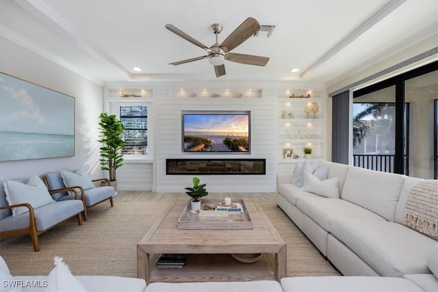 living room featuring plenty of natural light, ceiling fan, a tray ceiling, and light hardwood / wood-style flooring