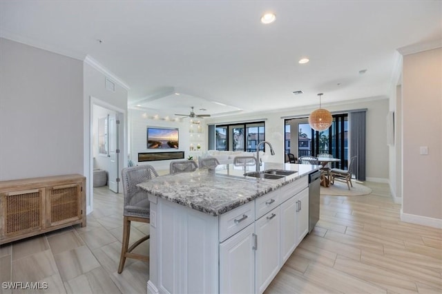 kitchen featuring pendant lighting, a kitchen island with sink, white cabinets, a kitchen breakfast bar, and sink