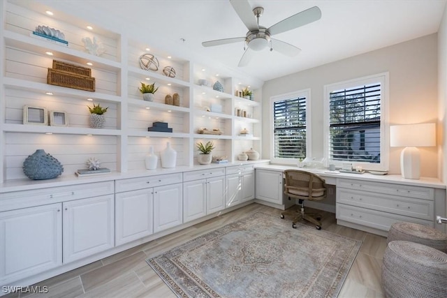 home office with built in desk and ceiling fan