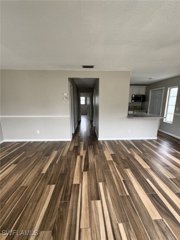 unfurnished living room featuring a textured ceiling and dark hardwood / wood-style floors