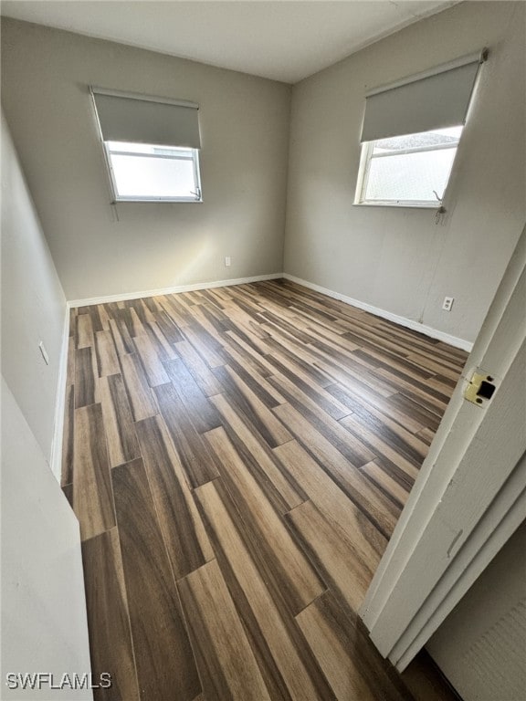 empty room featuring a healthy amount of sunlight and dark wood-type flooring