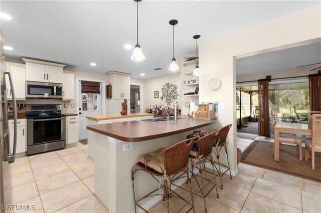 kitchen with sink, stainless steel appliances, a kitchen breakfast bar, kitchen peninsula, and decorative light fixtures