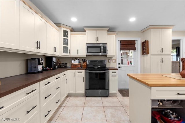 kitchen featuring butcher block counters, light tile patterned floors, and stainless steel appliances