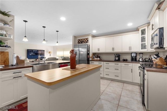 kitchen featuring stainless steel appliances, decorative light fixtures, a center island, butcher block countertops, and light tile patterned flooring