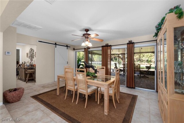 dining room featuring ceiling fan, a barn door, and light tile patterned floors