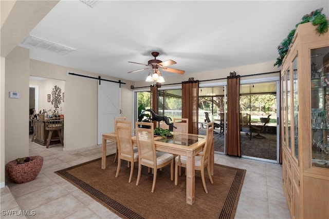 tiled dining area with a barn door and ceiling fan