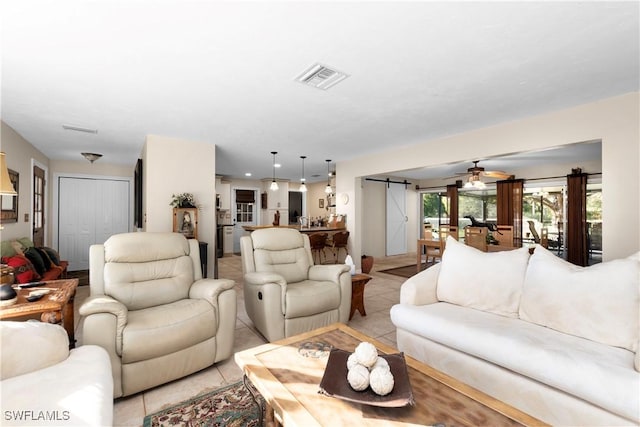 living room featuring a barn door, ceiling fan, and light tile patterned floors