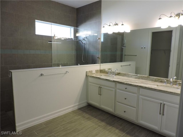 bathroom with a tile shower and vanity