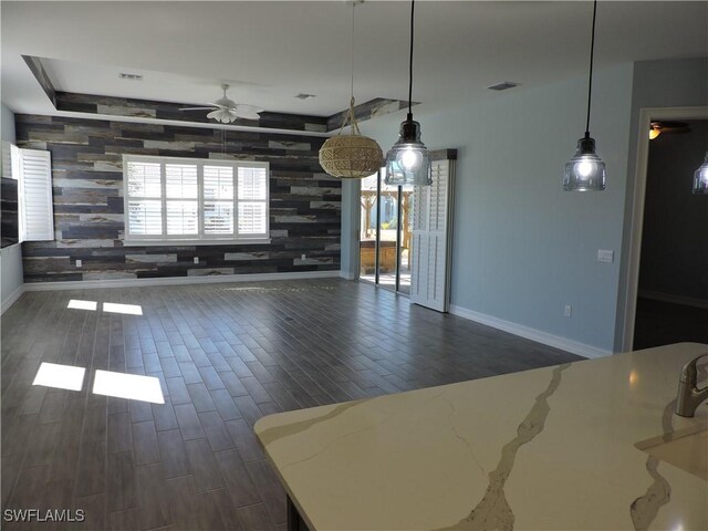 kitchen with hanging light fixtures, wooden walls, and ceiling fan