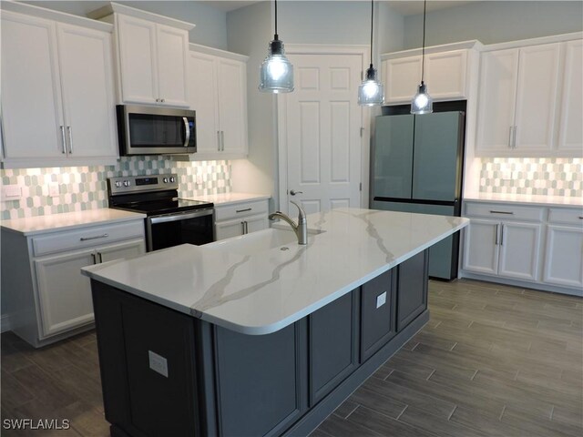 kitchen with white cabinets, pendant lighting, a center island with sink, and appliances with stainless steel finishes