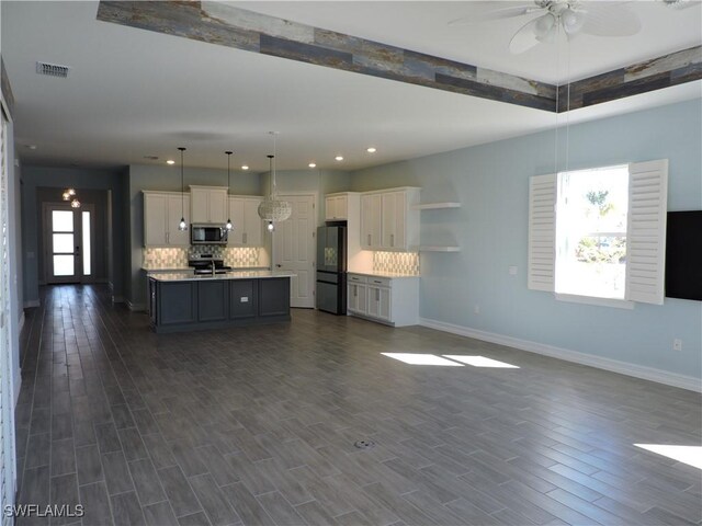 kitchen with stainless steel appliances, tasteful backsplash, an island with sink, pendant lighting, and white cabinets