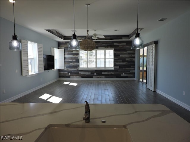 interior space featuring wooden walls, ceiling fan, pendant lighting, and dark hardwood / wood-style floors