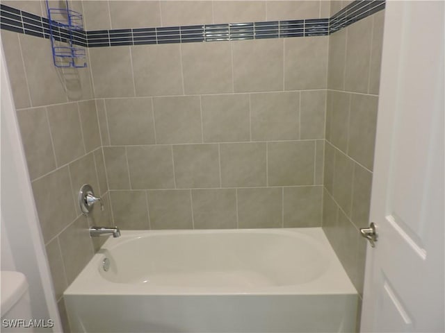 bathroom featuring toilet and tiled shower / bath