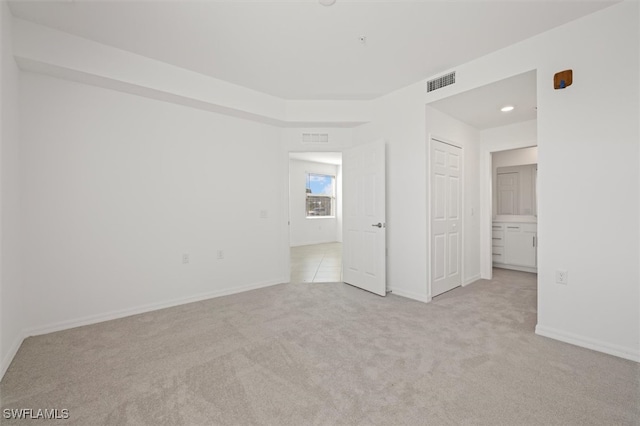 unfurnished bedroom featuring connected bathroom and light colored carpet